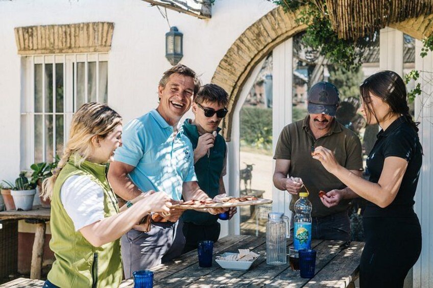 Eine Gruppe von Menschen versammelt sich um einen Tisch mit Essen, einer Flasche und blauen Tassen. 3