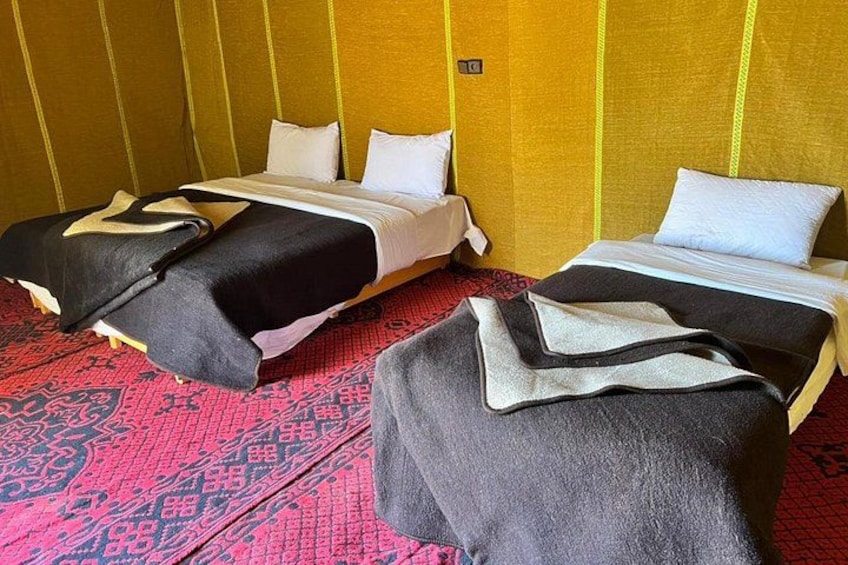 A hotel room with two beds, a red patterned carpet, and a yellow wall. 2