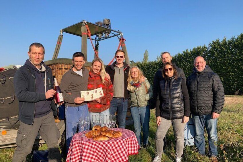 Un grupo de personas al aire libre junto a una mesa de picnic y una cesta de pan. 2