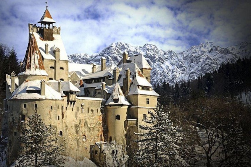 Un castillo con tejados nevados y montañas al fondo. 1