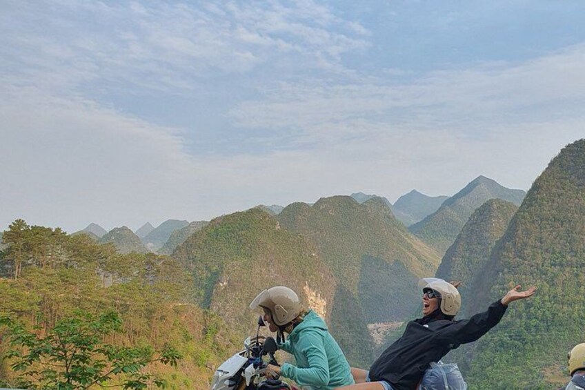 A mountainous landscape with a person in a green jacket and a helmet, another person in a black jacket and helmet, and a third person in a yellow helmet. 2