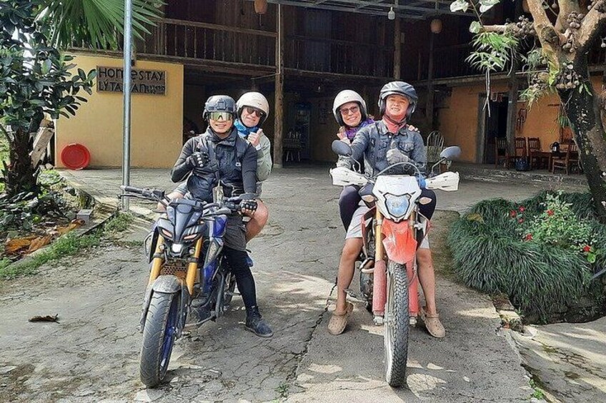 Three people on motorcycles in front of a building with a sign. 1