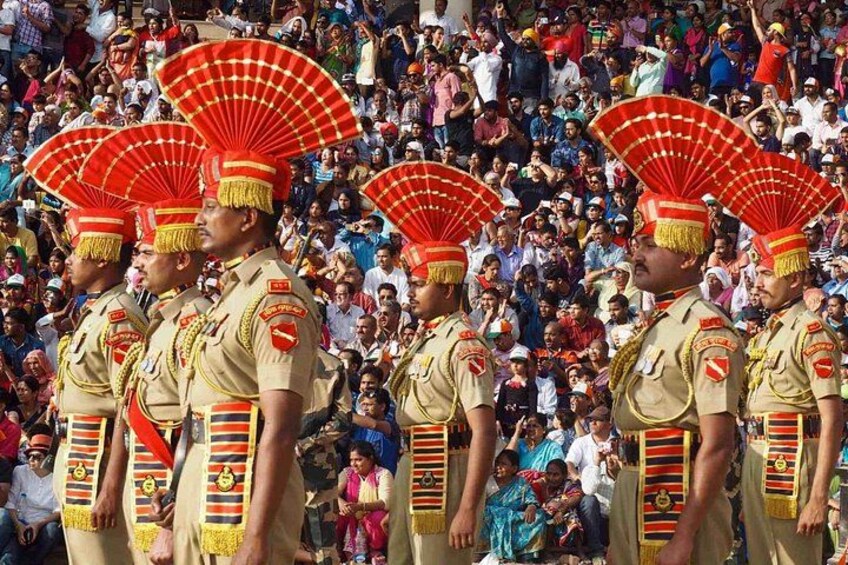 A group of uniformed personnel in ceremonial attire with red fans, standing in formation. 2