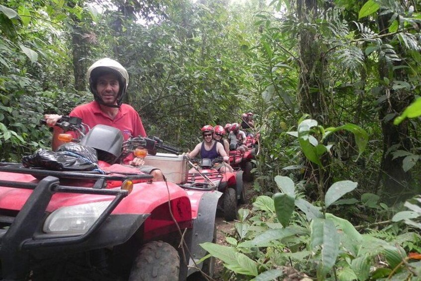Un gruppo di persone su un quad rosso in una fitta foresta. 1