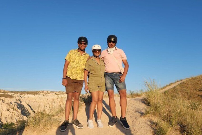 Three people standing on a dirt path in a desert landscape. 4