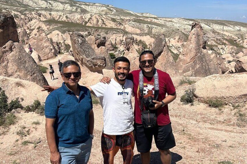 Three people standing in a rocky landscape with a clear sky. 5