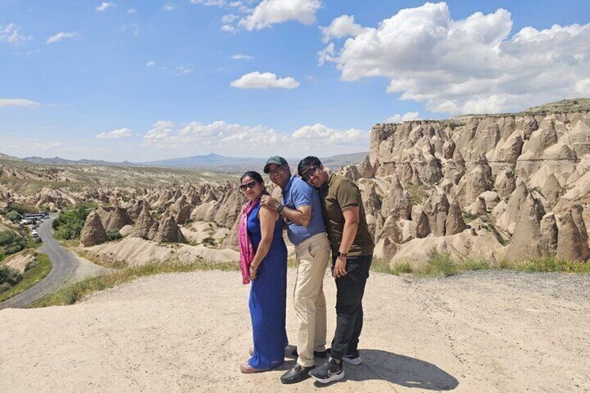 A group of people standing on a dirt path with a desert landscape and rock formations in the background. 2