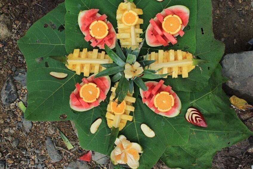 A large green leaf with carved fruits and vegetables arranged in a symmetrical pattern. 4