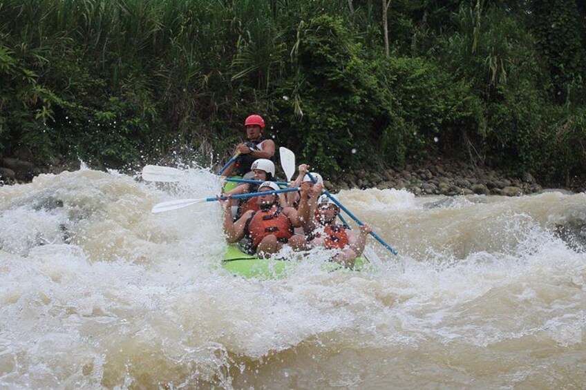 A group of people kayaking on a river surrounded by dense greenery. 1