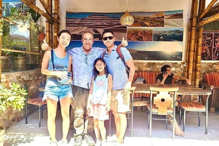 Una familia de cuatro personas en un restaurante al aire libre con decoración de bambú y vistas al paisaje. 3