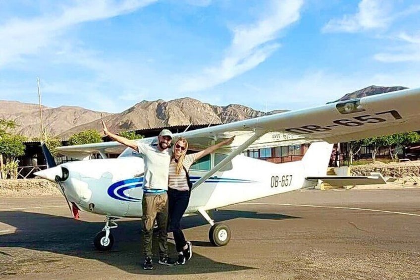 Un avión pequeño con el número de registro 'DB-657' estacionado en una plataforma de tarmac con montañas al fondo. 4