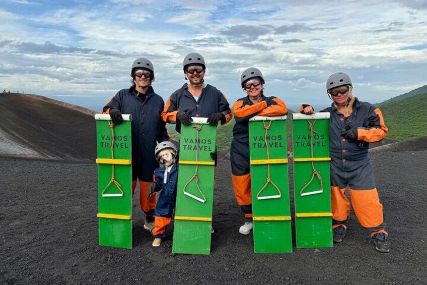 A group of people holding green and orange objects with 'VAMOS TRAVEL' text, standing on a barren landscape. 3