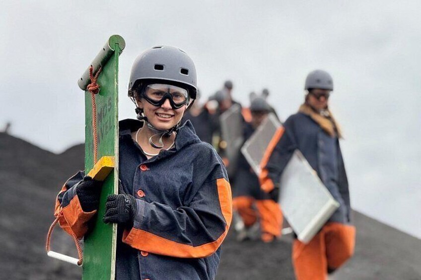 A person holding a green and yellow object, wearing a helmet and gloves, with a group in the background. 4