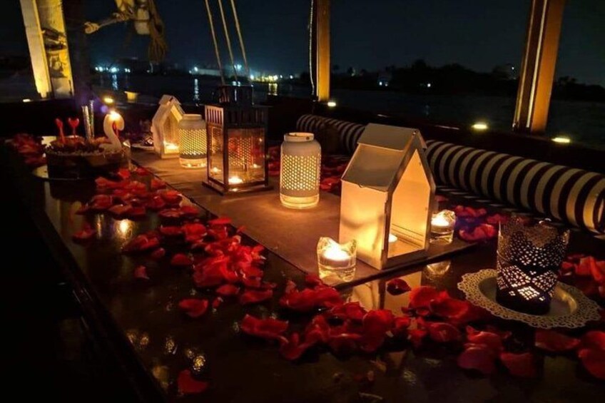 Ambiente romántico con velas, faroles y pétalos de rosa en un balcón con vistas al agua. 2