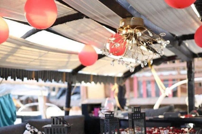 Un puesto de mercado con un candelabro decorativo, adornos colgantes rojos y varios artículos a la venta. 3