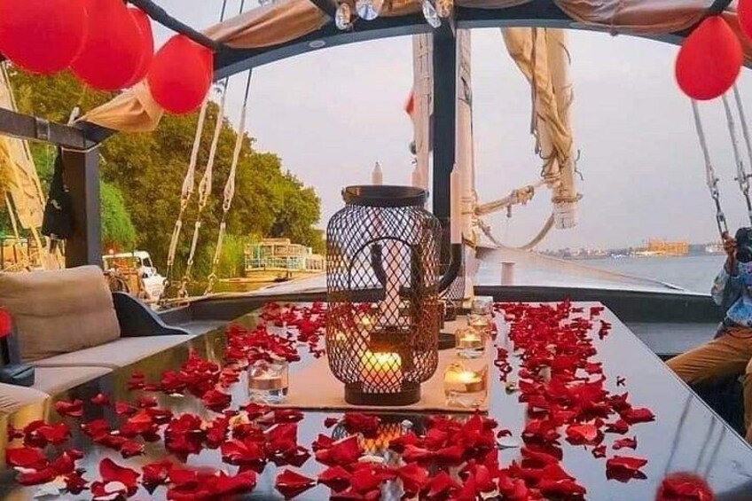 Una mesa con pétalos de rosa, un farol y globos rojos en un bote. 4