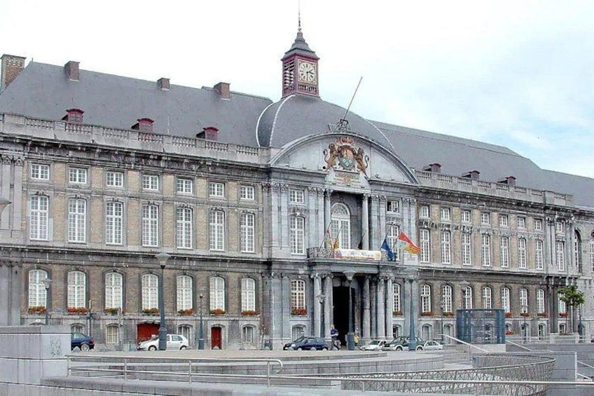 A large, historic building with a clock tower, multiple flags, and a prominent entrance. 3