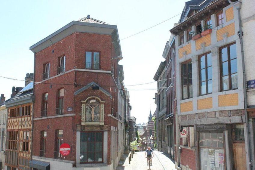 A narrow street with buildings on either side, a cyclist in the distance, and a no-entry sign on the left. 2