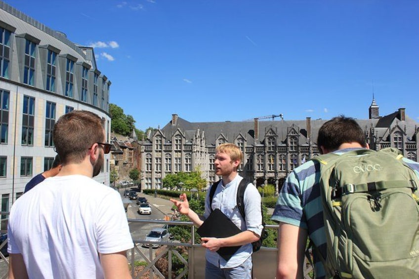 Trois personnes se tiennent sur un balcon, d’où elles peuvent admirer un bâtiment historique sous un ciel dégagé. 1