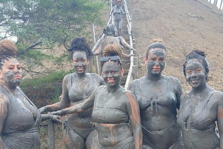 Un groupe de personnes couvertes de boue, debout près d’une structure en bois. 4