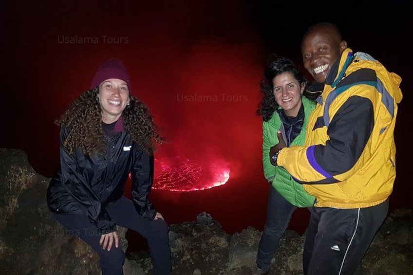 Tres personas cerca de un flujo de lava con un resplandor rojo. 1
