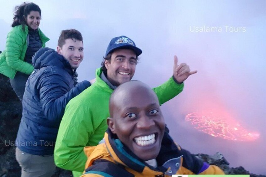 Un grupo de personas en una montaña, con un flujo de lava incandescente al fondo. 5