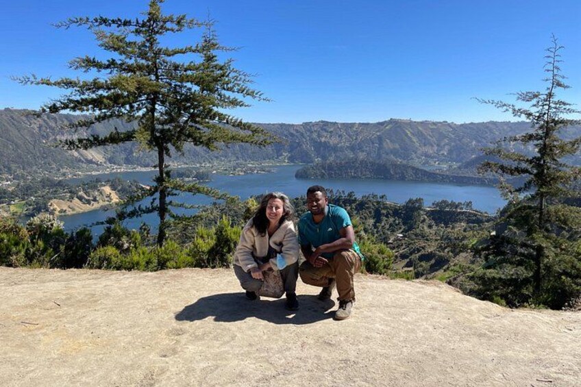 Two people posing on a hill with a lake and mountains in the background. 3