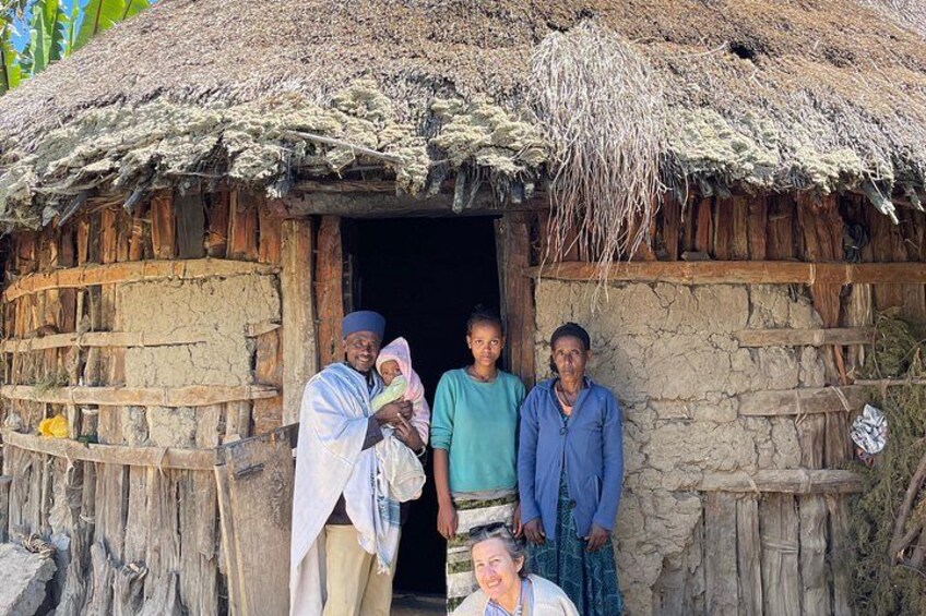 A traditional thatched-roof hut with a family standing in front. 5