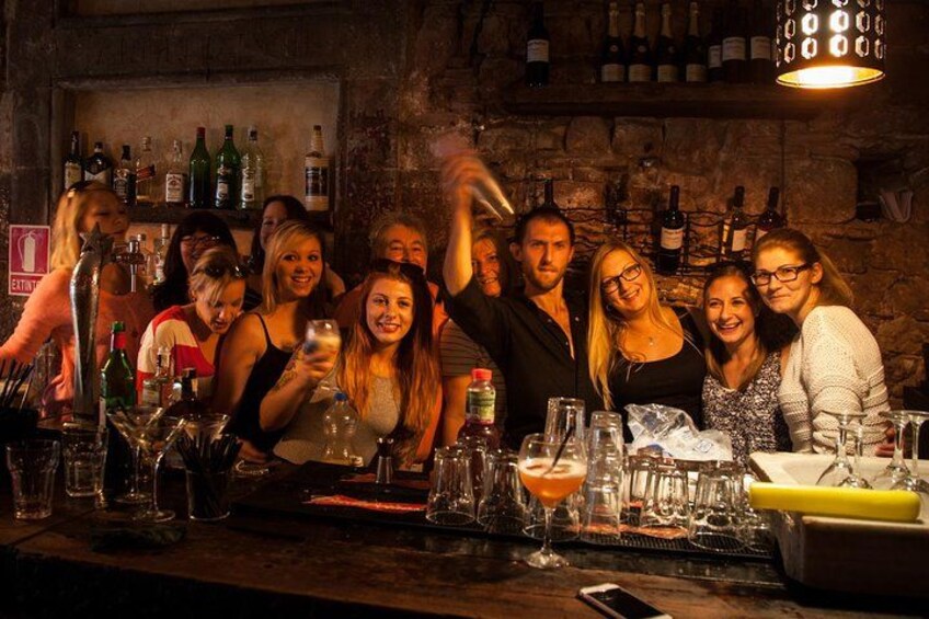 En grupp människor på en bar, med flaskor och glas på bardisken. 4
