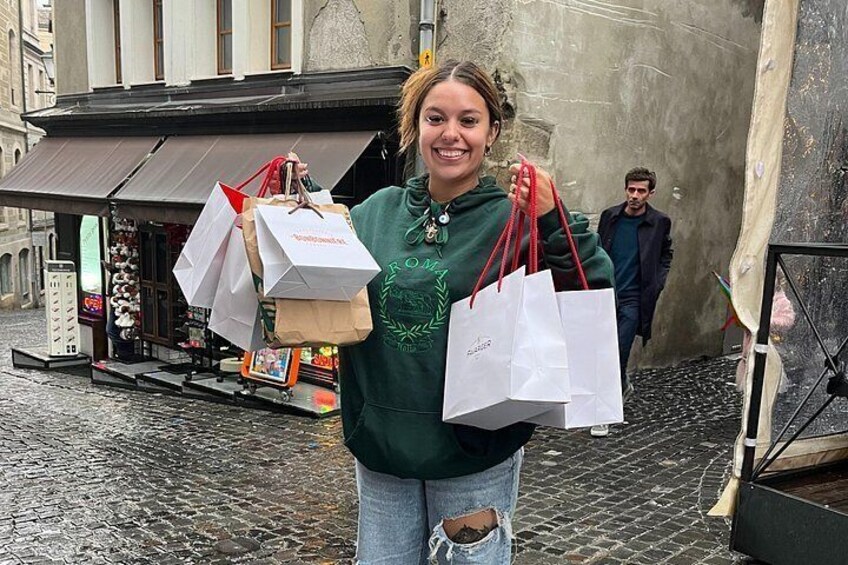 Una persona sosteniendo bolsas de compras en una calle urbana con adoquines y un edificio con un cartel. 4