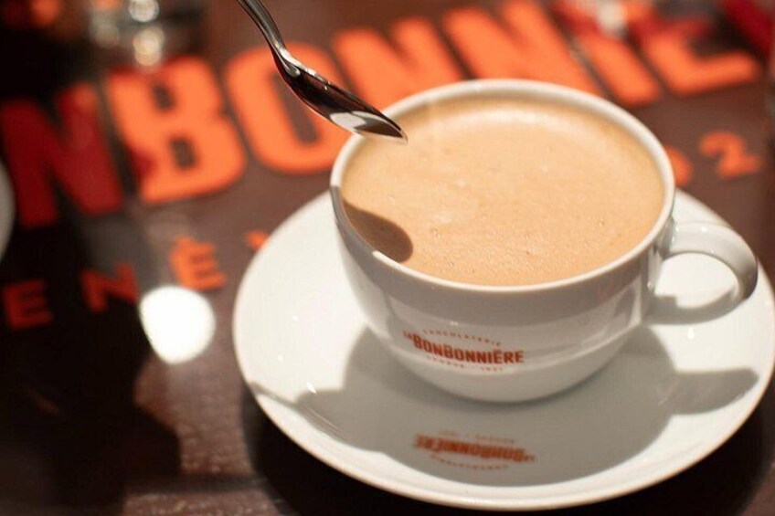 Una taza de café con una cuchara, sobre un plato, con texto en la taza y la mesa. 2