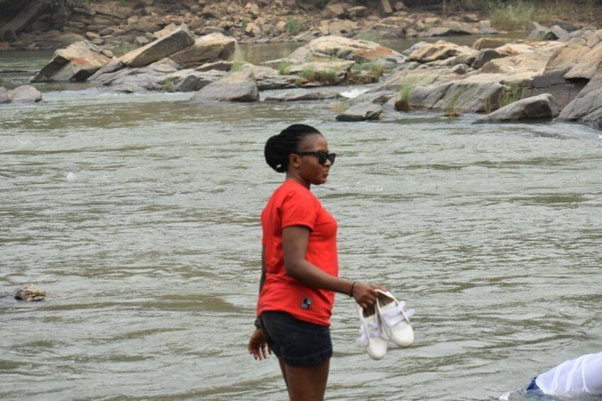 A person standing by a river with rocks and water. 2