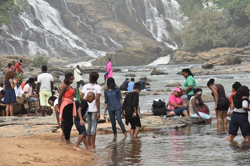 A group of people by a river with a waterfall in the background. 5