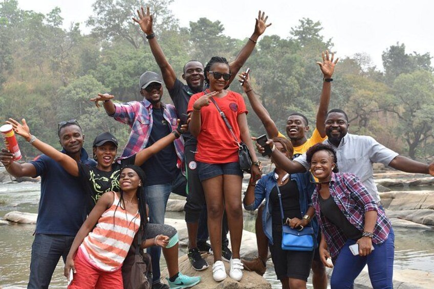 A group of people standing on rocks by a river. 4