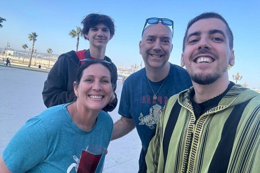 A group of people taking a selfie in an open area with palm trees and a clear sky. 5