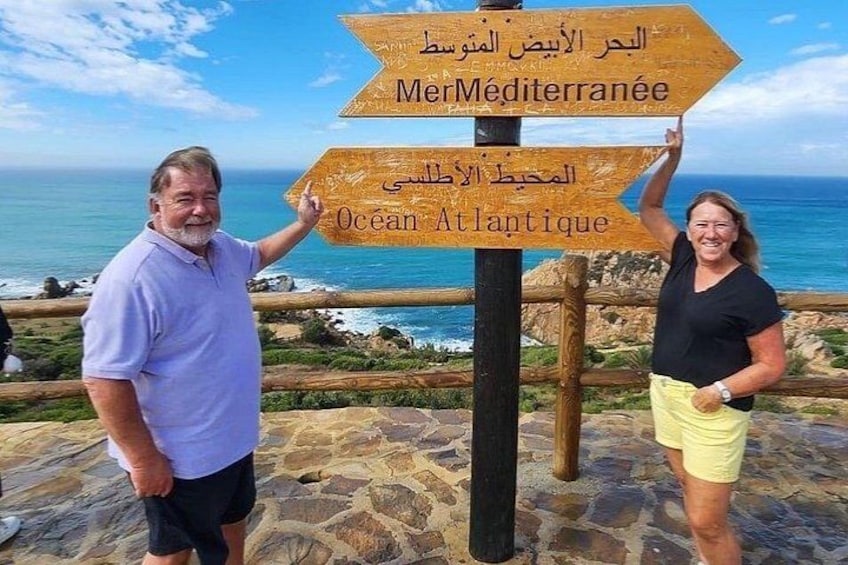 Dos personas de pie junto a un cartel con indicaciones hacia el Mar Mediterráneo y el Océano Atlántico. 2
