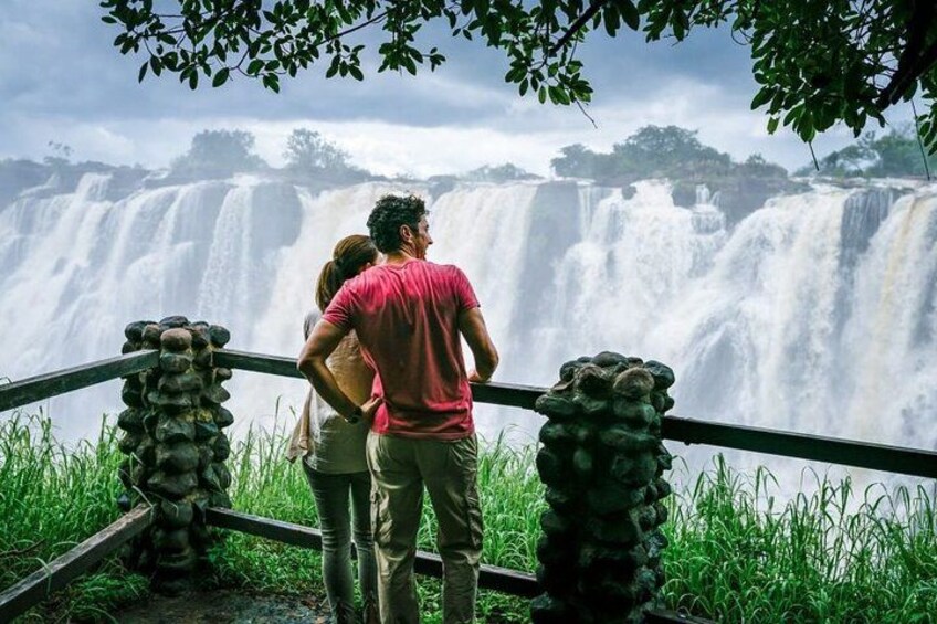 Una cascada con barandilla en primer plano y una persona de pie detrás. 3