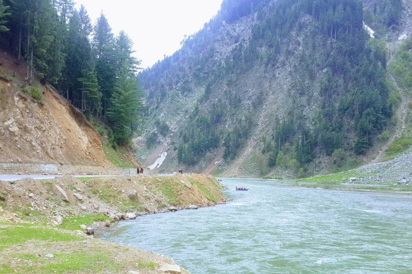 A river flowing through a mountainous area with a road alongside it. 3