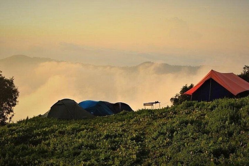 A mountainous landscape with tents and a red-roofed structure. 1
