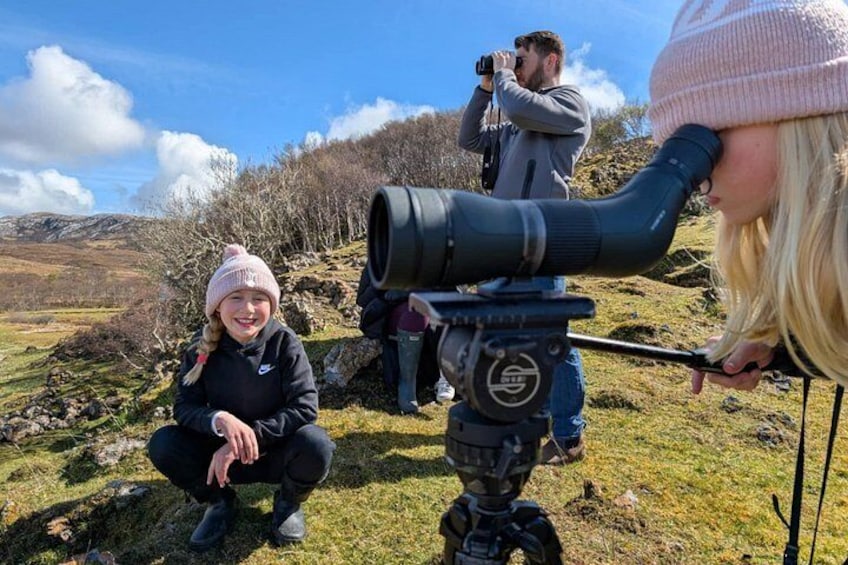 A person using a large telescope on a grassy hill with a clear sky. 4