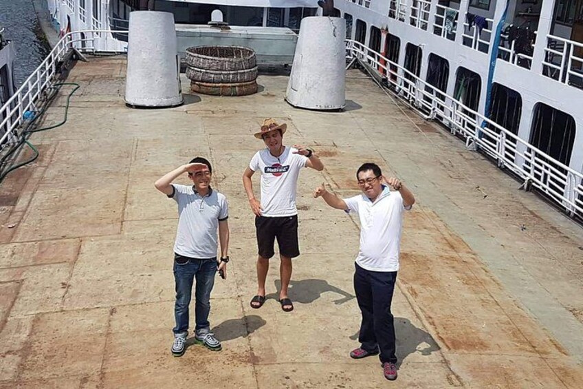 Tres personas en la cubierta de un barco, con barandilla y defensas. 1