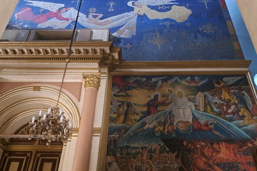 Kirkeinteriør med et stort muralmaleri, en lysekrone og klassisk arkitektur. 3