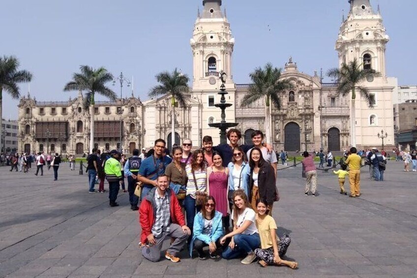 A group of people posing in front of a historic building with two towers. 4