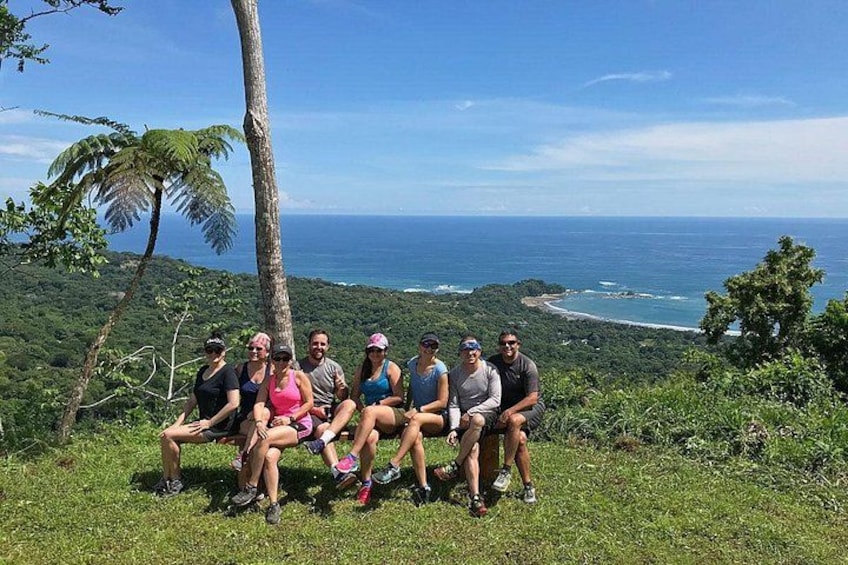 Un grupo de personas sentadas en una colina cubierta de hierba, con vistas a la costa y un cielo despejado. 5