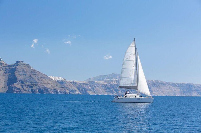 A sailboat on calm blue waters with a mountainous coastline in the background. 3