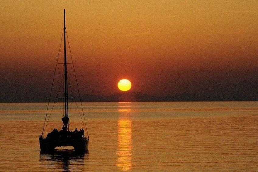 Ein Segelboot auf ruhigem Wasser während des Sonnenuntergangs, die Sonne tief am Horizont. 4