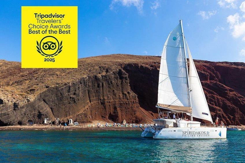 A sailboat named SPIRIDAKOS FR sailing on turquoise water with a rocky cliff in the background. 2