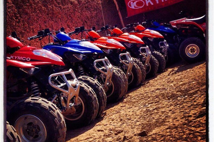 A row of quad bikes parked in a line. 2