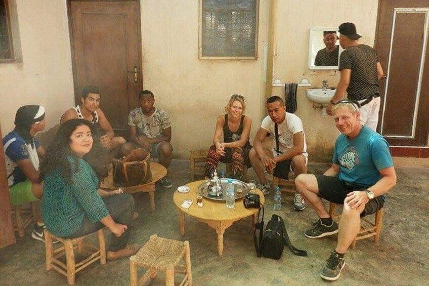A group of people sitting around a table in a room with a door and a mirror on the wall. 4