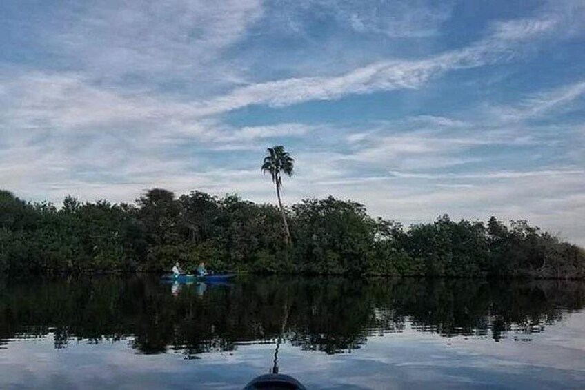 A calm lake with a boat and a person in the distance, surrounded by dense forest. 2